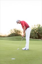 Hispanic golfer putting on golf course