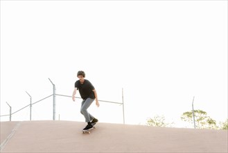 Hispanic man skateboarding in skate park
