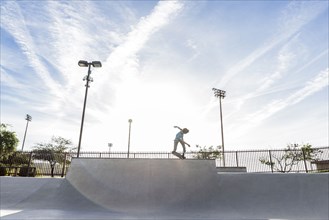 Hispanic man riding skateboard at skate park