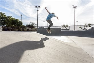 Hispanic man performing mid-air trick on skateboard
