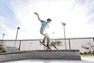 Hispanic man riding skateboard in skate park