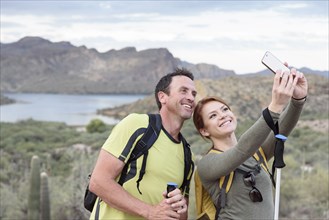 Hikers posing for cell phone selfie in desert