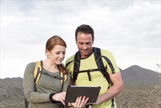 Hikers using digital tablet in desert