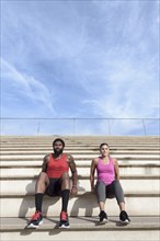 Man and woman doing triceps dips on bleachers
