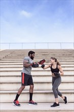 Trainer and woman boxing on bleachers