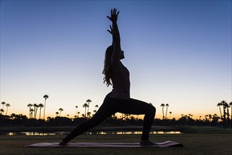 Silhouette of Hispanic woman performing yoga at sunset