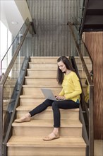 Mixed race woman sitting on staircase using laptop