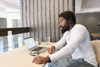 Black man wearing headset using laptop