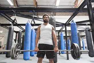 Black man lifting barbell in gymnasium