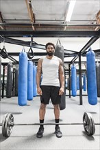 Black man standing near barbell in gymnasium