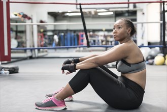 Black woman sitting on floor in boxing ring