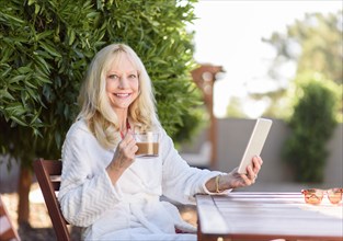 Caucasian woman drinking coffee and using digital tablet