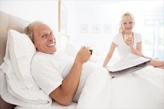 Caucasian couple drinking coffee and juice in bed