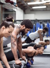 Man and women doing push-ups with kettlebells