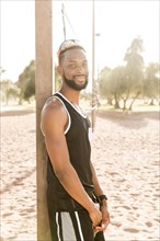 Portrait of smiling black man leaning on beach volleyball net