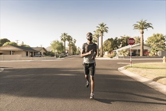Black man running on street in neighborhood