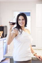 Smiling Caucasian woman toasting with red wine