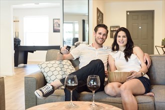 Smiling Caucasian couple sitting on sofa watching television