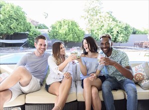 Smiling friends with cold drinks toasting outdoors