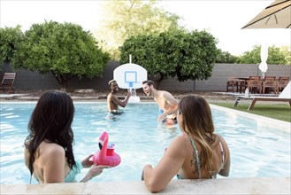 Women watching men playing in swimming pool
