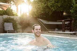 Smiling Caucasian man relaxing in swimming pool