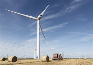 Bales of hay and tractor near wind turbine