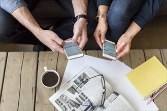 Hands of Caucasian couple texting on cell phones