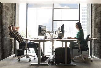 Caucasian man and woman using computers in office
