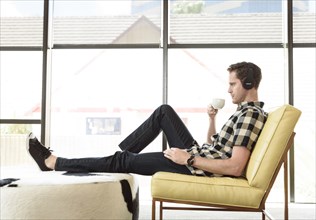 Caucasian man drinking coffee and listening to headphones
