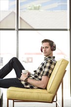 Caucasian man drinking coffee and listening to headphones