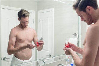 Caucasian man squeezing lotion onto hand in bathroom