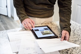 Caucasian man using digital tablet and holding paperwork