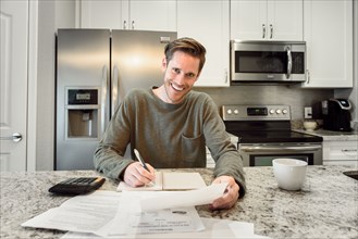 Smiling Caucasian man writing notes and reading paperwork