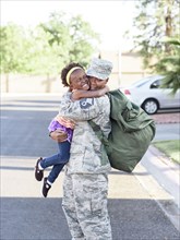 Black woman soldier hugging daughter in street