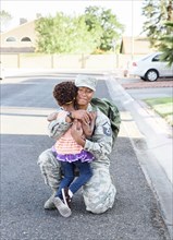 Black woman soldier greeting daughter in street