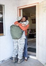 Black woman soldier hugging man in doorway
