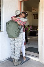 Black woman soldier hugging daughter in doorway