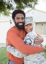 Portrait of black woman soldier hugging man