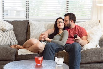 Caucasian man kissing cheek of woman on sofa