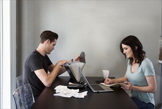 Caucasian woman writing notes near laptop while man searches files