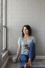 Caucasian woman sitting on floor texting on cell phone