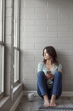 Caucasian woman sitting on floor texting on cell phone