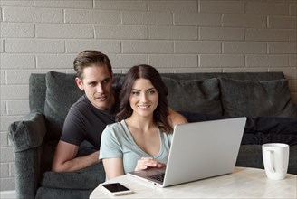 Caucasian couple on sofa using laptop