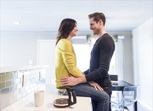 Caucasian couple embracing on kitchen counter