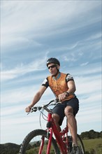 Male cyclist riding under blue sky