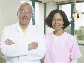 Senior Asian male dentist with African female dental assistant