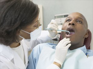 African female dentist examining male patient