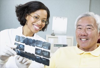 African female dentist showing x-rays to senior male patient