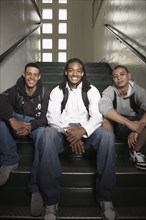 Group of young men sitting on stairs at school