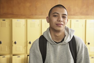 Young Asian man next to school lockers